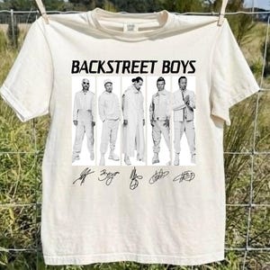 Könnte beinhalten: Ein cremefarbenes Kurzarm-T-Shirt mit einem schwarzen Grafikdruck der Backstreet Boys. Das Design zeigt fünf einzelne Schwarz-Weiß-Porträts der Bandmitglieder, den Schriftzug BACKSTREET BOYS sowie fünf verschiedene Unterschriften darunter.