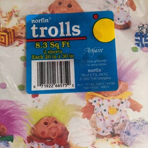 Pu&ograve; includere: Un pacchetto di carta da regalo blu e gialla con un'illustrazione colorata di troll. Il pacchetto dice "norfin trolls 8.3 Sq Ft 2 sheets Each 20 in x 30 in".