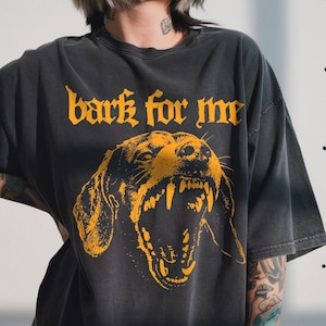 Black vintage t-shirt featuring a high-contrast orange graphic of a snarling Dachshund dog showing teeth, with the text bark for me in gothic font above it, grunge streetwear style.
