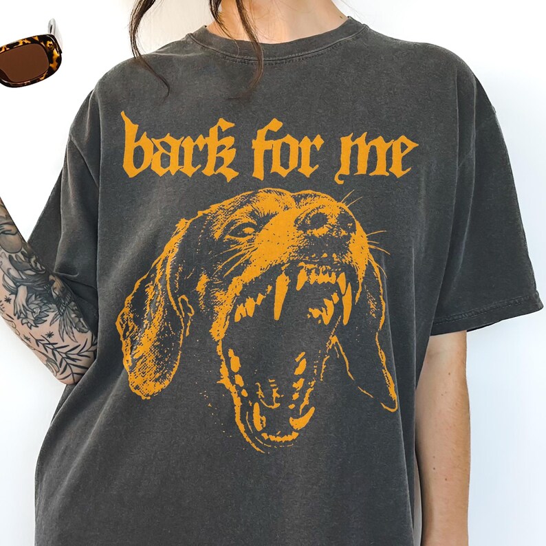 Black vintage t-shirt featuring a high-contrast orange graphic of a snarling Dachshund dog showing teeth, with the text bark for me in gothic font above it, grunge streetwear style.