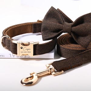 Op de afbeelding: Een bruine hondenriem, vlinderdas en riemset met visgraatmotief. De halsband heeft een goudkleurige gesp met de naam "Cooper" en een telefoonnummer. De vlinderdas is voorgeknoopt.