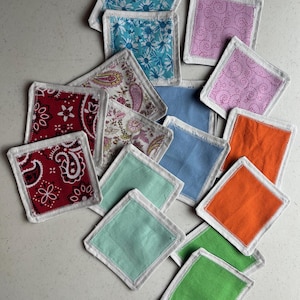 May include: A set of three ceramic mugs with a speckled, cream-colored glaze. Each mug features a different hand-painted floral design in shades of blue, green, and yellow. The mugs have a simple, rounded shape and a comfortable handle.