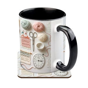 May include: White ceramic mug with a black interior and handle, featuring a knitting-themed design. The design includes yarn balls, knitting needles, scissors, and the name "Sophia". A matching coaster is also visible.