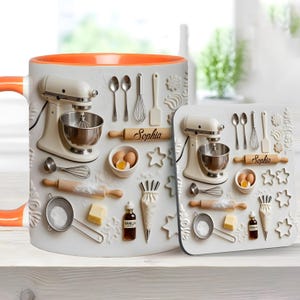 May include: A white ceramic mug and square coaster set featuring a 3D-style print of baking tools including a cream stand mixer, a rolling pin labeled "Sophia," a bowl with eggs, a whisk, a spatula, a sieve, butter, and a vanilla bottle.