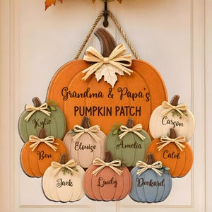 Könnte beinhalten: Ein großes orangefarbenes Kürbisschild aus Holz mit der Aufschrift Grandma & Papa's PUMPKIN PATCH, das neun kleinere, befestigte Kürbisse in verschiedenen Farben zeigt, die jeweils mit den Namen Kylie, Ben, Jack, Elouise, Lindy, Amelia, Deckard, Caleb und Carson personalisiert sind.