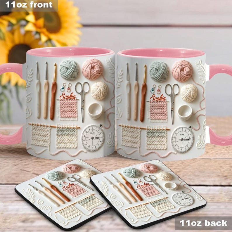 May include: White ceramic mugs with pink interiors and handles, featuring embossed knitting and crochet tools, yarn balls, and the name "Sophia." Matching coasters with the same design are also visible. The text "11oz front" and "11oz back" are displayed.