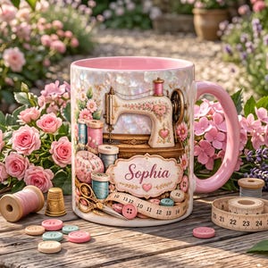 Könnte beinhalten: Ein Keramikbecher mit rosa Innenseite und Henkel, bedruckt mit einer Illustration einer alten Nähmaschine, Garnrollen, einem Nadelkissen, einer Schere und einem Maßband, wobei der Name Sophia in einer dekorativen Schriftart abgebildet ist.