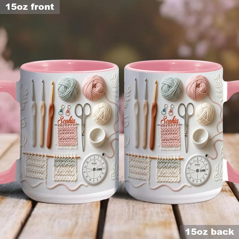 May include: Two white 15oz ceramic mugs with pink handles and rims. The mugs feature a design of knitting and crochet tools, yarn balls, and the name "Sophia". The design includes a stopwatch and a knitted swatch.