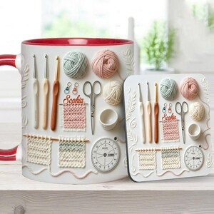 May include: White ceramic mug and coaster set featuring a crochet-themed design. The design includes yarn balls, crochet hooks, scissors, and the name "Sophia". The mug has a red interior and handle.
