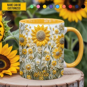 Pode incluir: Uma caneca de cerâmica branca com alça e borda amarelas, adornada com girassóis amarelos em relevo e pequenas flores brancas. O nome "Alicia" está escrito na caneca. O texto "NAME CAN BE CUSTOMIZED" está em uma caixa amarela.