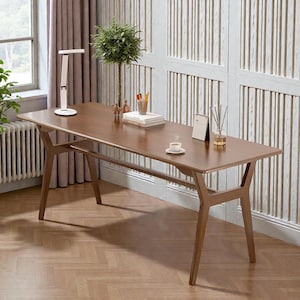 May include: A mid-century modern style wooden desk with a dark brown finish. The desk has a rectangular top and angled legs. A small plant, books, and a lamp are on the desk. The desk is 60 inches long.