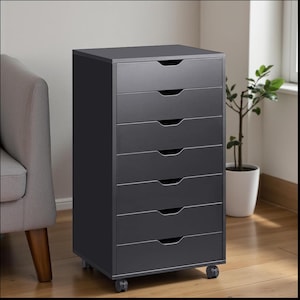 May include: A dark gray, seven-drawer storage cabinet on wheels. The cabinet has a rectangular shape with a flat top and recessed drawer pulls. The drawers are evenly spaced and the cabinet is set against a neutral background. The cabinet is a practical storage solution.