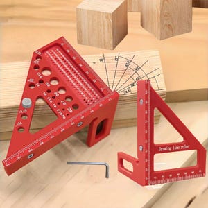 May include: Two red aluminum carpenter's squares with measurement markings and a hex key. One square is labeled "Drawing line ruler". The squares are designed for woodworking and include angle and measurement guides. The squares are on a wooden surface.