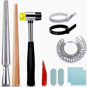 Op de afbeelding: Een sieradenmakerskit met diverse gereedschappen. Inclusief een zilveren ringmaat, houten doorn, een hamer met zwarte handgreep, ringmaatbanden, een ringmatenset, een rode priem, twee groene polijstpads en twee blauwe poetsdoeken.