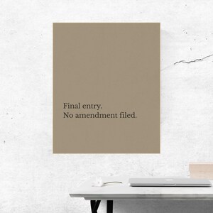 Könnte beinhalten: Ein rechteckiger Druck in Beige mit dem Text "Final entry. No amendment filed." in Schwarz. Der Druck wird an einer weißen Wand über einem weißen Schreibtisch mit einem Laptop angezeigt.