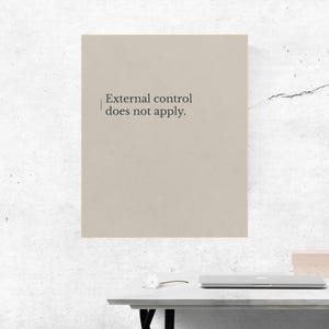 Puede incluir: Impresión de color beige con el texto "External control does not apply" en una fuente serif. La impresión se muestra en una pared blanca. Una mesa blanca y un ordenador portátil son visibles en primer plano.