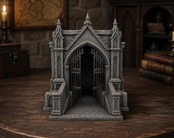 May include: A gray stone miniature gothic gatehouse structure featuring intricate masonry details, pointed arches, and tall spires. The front displays an open metal gate leading to a set of stairs that descend into a dark, recessed interior space.