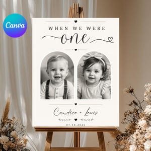 May include: A black and white sign on a wooden easel with the text "WHEN WE WERE ONE" above two photos of babies. The sign also includes the names "Candice + Lewis" and the date "07.10.2026".