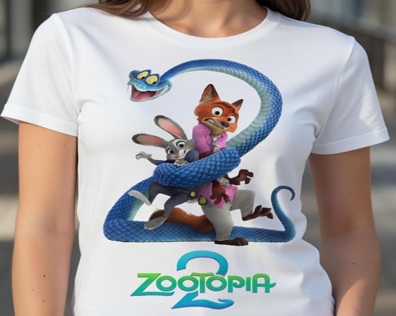 Peut inclure: T-shirt blanc avec un motif color&eacute; du film d'animation Zootopie. Le design pr&eacute;sente les personnages Judy Hopps, Nick Wilde et un serpent bleu formant le chiffre 2, avec le titre du film en dessous.
