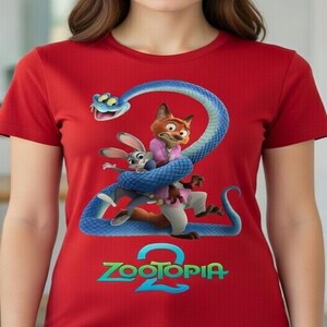 Peut inclure: T-shirt rouge avec un graphisme color&eacute; du film d'animation "Zootopia 2". Le motif comprend un serpent bleu, un renard et un lapin, avec le titre du film en vert et bleu. Le t-shirt est &agrave; manches courtes.
