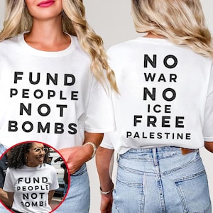 May include: White t-shirts with black text. One shirt reads "FUND PEOPLE NOT BOMBS" and the other reads "NO WAR NO ICE FREE PALESTINE". The shirts are paired with blue jeans.