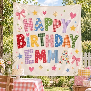 May include: A cream-colored fabric banner featuring the text HAPPY BIRTHDAY EMMA in large, multi-colored patterned letters. The design includes pink bows, yellow and blue stars, and small hearts scattered across the background surface.