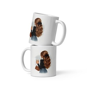 Puede incluir: Dos tazas de café de cerámica blanca apiladas una encima de la otra. Cada taza presenta una ilustración de una persona con cabello castaño largo, con una blusa negra y jeans azules, sosteniendo una taza de café y un bolso marrón.
