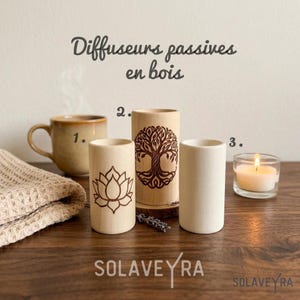 Peut inclure: Trois diffuseurs passifs cylindriques en bois, dont deux avec des motifs gravés au laser d'une fleur de lotus et d'un arbre, avec le texte Diffuseurs passives en bois et SOLAVEYRA. Les objets sont disposés sur une surface en bois.