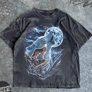 May include: Dark gray t-shirt featuring a wolf howling at the moon. The graphic includes a full moon, mountains, and a starry sky. The shirt has the text "Mad Kitten" in the upper right corner and "Pepper" in a circle at the bottom left.