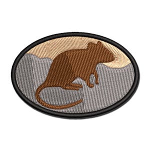 May include: Embroidered patch featuring a brown rodent silhouette set against a backdrop of gray mountains and a tan sun. The oval patch has a black border. The rodent is depicted in profile, with a long tail and detailed fur.