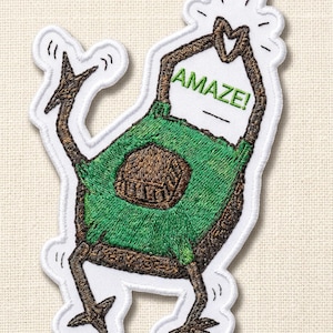 May include: Embroidered patch featuring a cartoon avocado character with brown arms and legs, a green body, and a brown pit. The word "AMAZE!" is above the avocado's head. The patch has a white border.