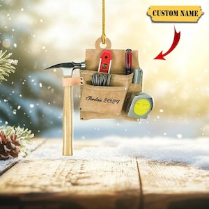 May include: A tan tool belt ornament featuring a hammer, a red level, a screwdriver, and a yellow tape measure. The belt is inscribed with the text Jordan 2024. A yellow banner at the top right displays the text CUSTOM NAME with a red arrow.