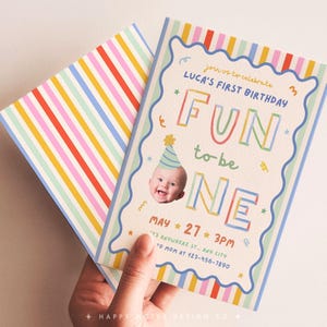 May include: A vibrant birthday invitation featuring the text "FUN to be ONE" and a photo of a baby in a party hat. The invitation has a striped pattern on the back and includes the date, time, and location of the party.
