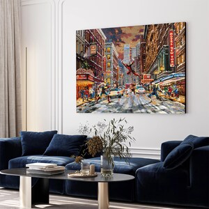 May include: A large canvas print depicts a snowy New York City street scene with figures in action. The artwork features a superhero in flight, buildings with neon signs, and pedestrians. The color palette includes reds, blues, and yellows, creating a dynamic urban landscape.