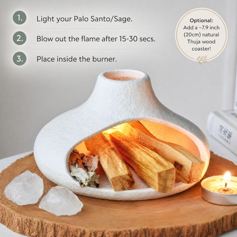 May include: A white ceramic burner with an opening to hold Palo Santo sticks. The burner sits on a wooden coaster, with two clear quartz crystals and a lit candle nearby. Instructions are printed on the image.