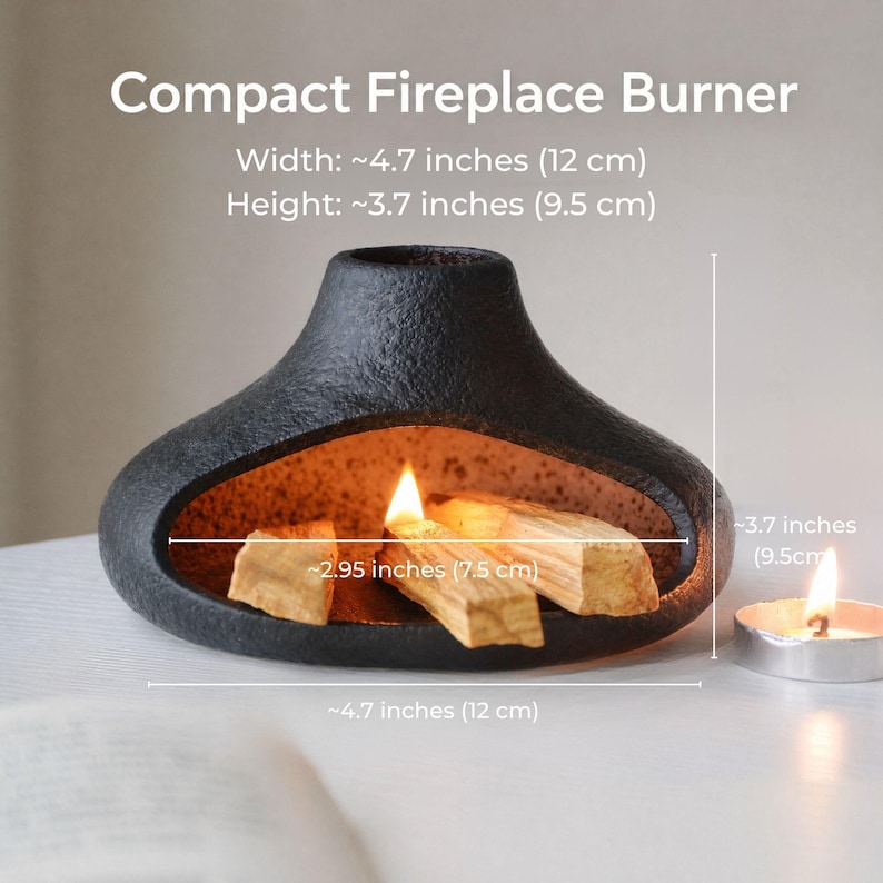 May include: A black, textured, ceramic compact fireplace burner with a burning flame and wooden incense sticks inside. The burner is approximately 4.7 inches (12 cm) wide and 3.7 inches (9.5 cm) high. A small candle is to the right of the burner.