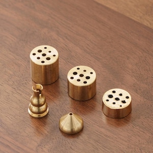 Könnte beinhalten: Ein Set aus drei Keramikbechern mit gesprenkelter, matter Oberfläche. Die Becher sind in Creme-, Hellgrau- und Dunkelgrautönen gehalten. Jeder Becher hat ein schlichtes, minimalistisches Design.