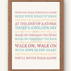 May include: A wooden framed print featuring the lyrics "When you walk through a storm, hold your head up high..." in a variety of colours. The text is on a white background. A motivational piece of art.