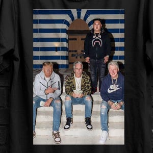 Könnte beinhalten: Schwarzes T-Shirt mit einem Foto von vier Personen, die auf Stufen sitzen. Das Bild auf dem Shirt zeigt die Gruppe vor einem Gebäude mit blau-weiß gestreiften Bögen. Das Shirt hat auch den Text "SEVENTHREE SEVEN" und eine "BUY 3 FREE" Grafik.