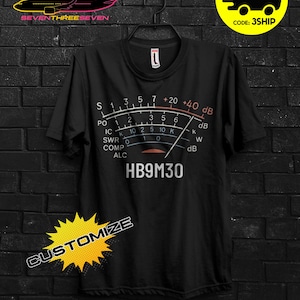 Può includere: T-shirt nera con grafica a misuratore e la scritta "HB9M30". La maglietta presenta anche la scritta "CUSTOMIZE" e una grafica gialla e nera con la scritta "BUY 3 FREE".