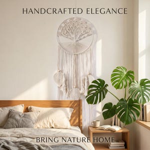 Puede incluir: Un tapiz de pared de macramé color crema con un diseño de árbol, con largas franjas y elementos decorativos. Se muestra el texto "HANDCRAFTED ELEGANCE" y "BRING NATURE HOME". La escena incluye una cama, una planta y una mesita de noche de madera.
