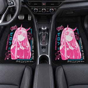 Puede incluir: Dos alfombrillas de coche negras con una vibrante ilustración de un personaje estilo anime en color rosa con cuernos. El diseño incluye el texto 002, Partner Killer y PISTIL OF THE FRANXX, junto a caracteres japoneses y líneas geométricas.