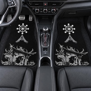 May include: A pair of black car floor mats featuring a white graphic print. The design includes a detailed illustration of a traditional East Asian temple structure at the bottom, with a pair of hands in a prayer gesture and a dharma wheel above.