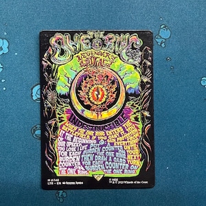 May include: A rectangular Magic: The Gathering trading card titled The One Ring, featuring a vibrant, psychedelic illustration of a fiery eye within a ring. The black card displays neon green, purple, and orange text detailing game rules.