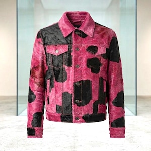 May include: A long-sleeve jacket featuring a vibrant pink and black cow-print pattern with a textured fur-like finish. The garment includes a classic collar, a front button-down closure with metallic buttons, and two chest pockets with buttoned flaps.