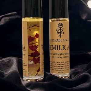 May include: Two glass roll-on bottles with black caps. One bottle has dried red petals inside. The other bottle has the text "NIGHTSHADE & NEC" and "REMILK A" with a rose graphic. The bottles are on a black, textured surface.