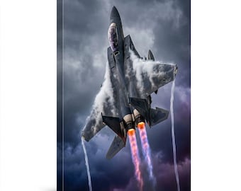 May include: A canvas print of a gray fighter jet soaring through a cloudy sky. The jet's engines emit orange and purple flames, with white vapor trails. The background features dark, dramatic clouds.