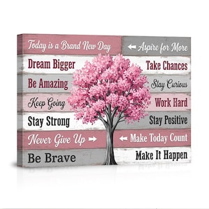 May include: A canvas print featuring a pink flowering tree with a gray trunk, set against a backdrop of pink and gray wooden planks. The print includes inspirational phrases such as "Dream Bigger" and "Make It Happen".