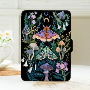 Könnte beinhalten: Eine schwarze E-Reader-Hülle mit einer farbenfrohen Illustration von zwei Nachtfaltern, verschiedenen Pilzen, Farnen und Wildblumen. Das Design zeigt einen Halbmond und ein Vollmondsymbol am oberen Rand auf einem dunklen Hintergrund mit botanischen Details.