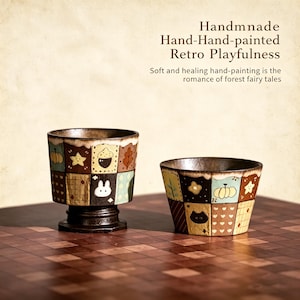Könnte beinhalten: Zwei handbemalte Keramikbecher mit Patchwork-Design. Die Becher zeigen Quadrate mit verschiedenen Motiven, darunter ein Stern, eine Eichel, ein Blatt und ein weißes Kaninchen. Der Text "Handmnade Hand-Hand-painted Retro Playfulness" ist sichtbar.